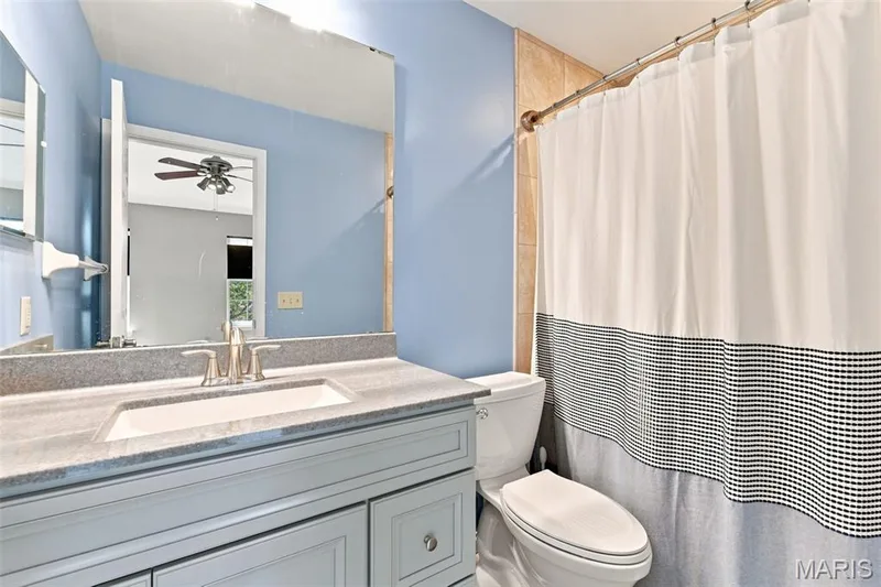 White vanity with an integrated rectangular sink, brushed nickel faucet, and a large wall-mounted mirror — 16561 Carriage View Court, Wildwood, MO 63040
