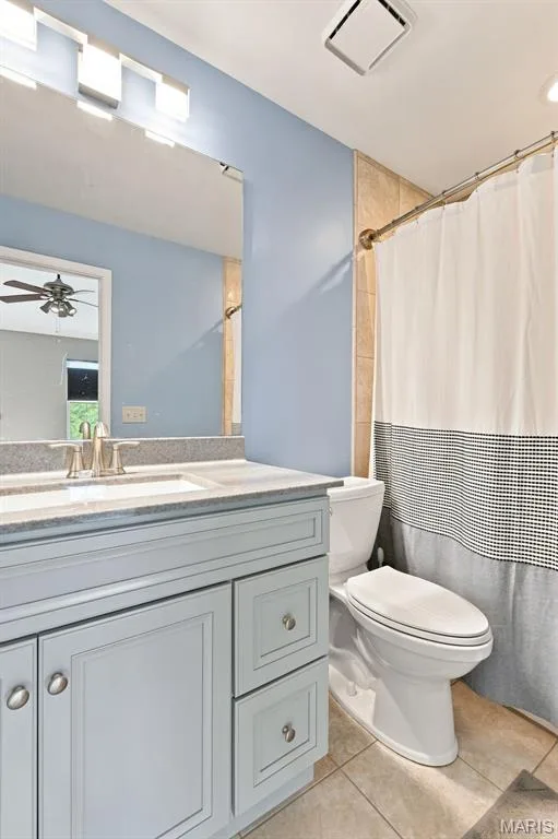 Bathroom featuring a single vanity with a stone countertop, an integrated sink, a large wall mirror, and a tiled shower surround — 16561 Carriage View Court, Wildwood, MO 63040