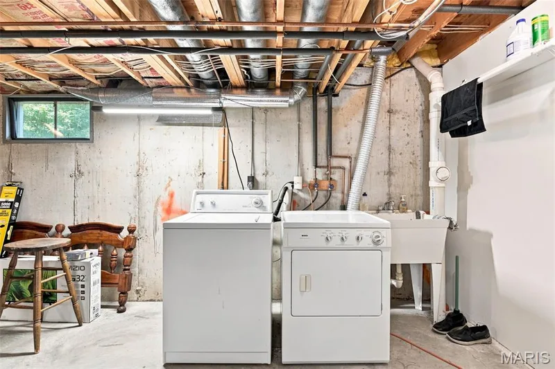 Washer and dryer appliances, concrete flooring, utility sink, and overhead fluorescent lighting — 16561 Carriage View Court, Wildwood, MO 63040
