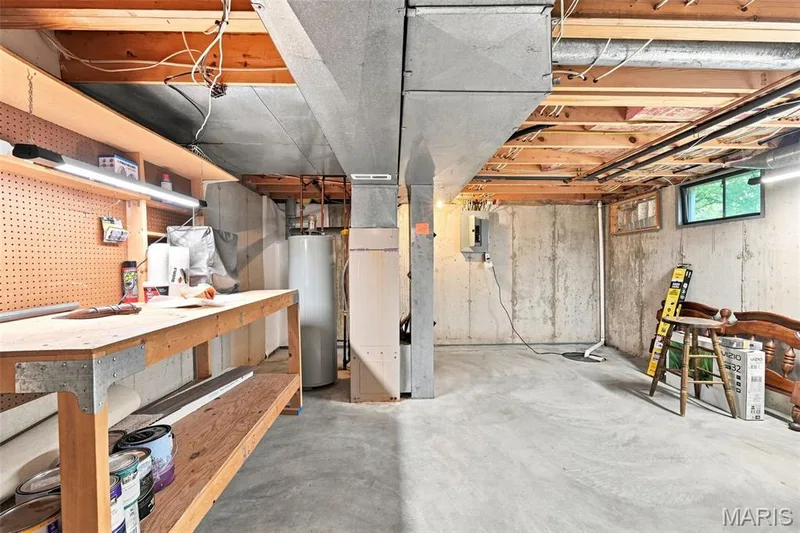 Unfinished basement featuring concrete flooring, a built-in workbench, exposed ceiling joists, and a window — 16561 Carriage View Court, Wildwood, MO 63040