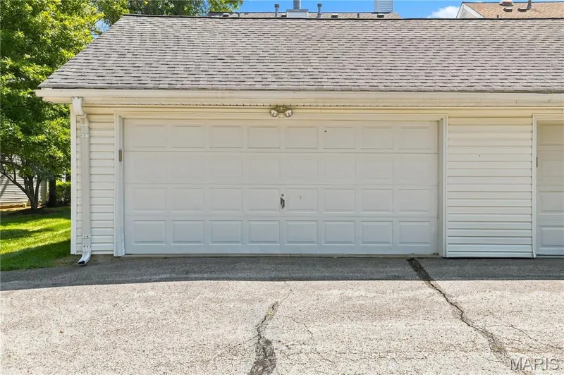 White paneled garage door with exterior lighting and a gabled roofline — 16561 Carriage View Court, Wildwood, MO 63040