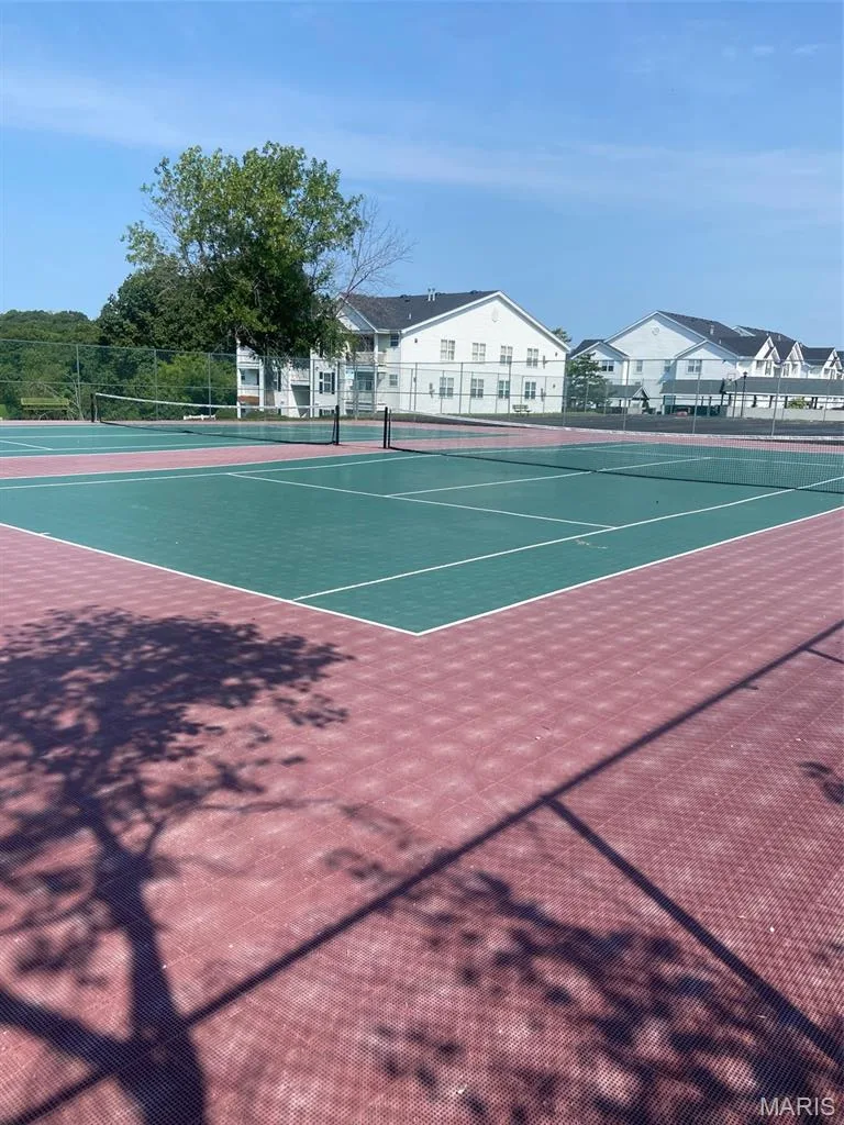 Tennis court with green and red surface, white court lines, and a black net — 16561 Carriage View Court, Wildwood, MO 63040