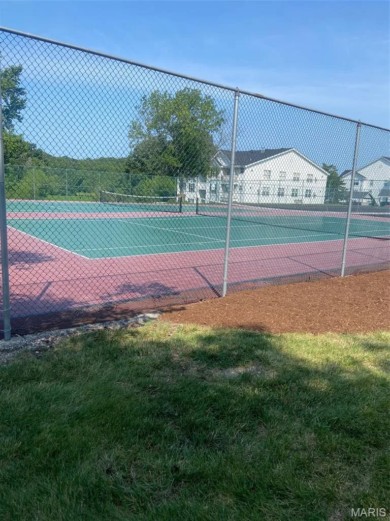 Outdoor tennis court with a chain link fence and a natural grass foreground — 16561 Carriage View Court, Wildwood, MO 63040