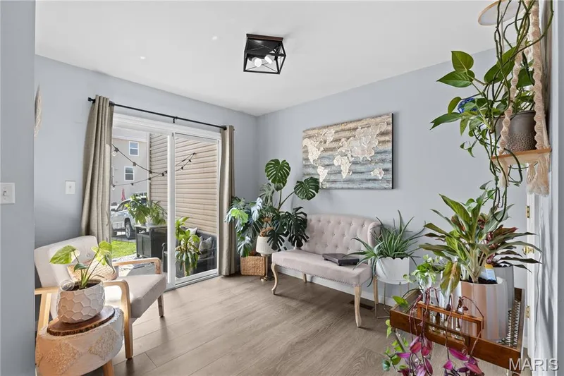 Sliding glass door opening to outdoor space, complemented by light wood-finish flooring and light blue wall paint — 349 Shady Rock Lane, O'Fallon, MO 63368