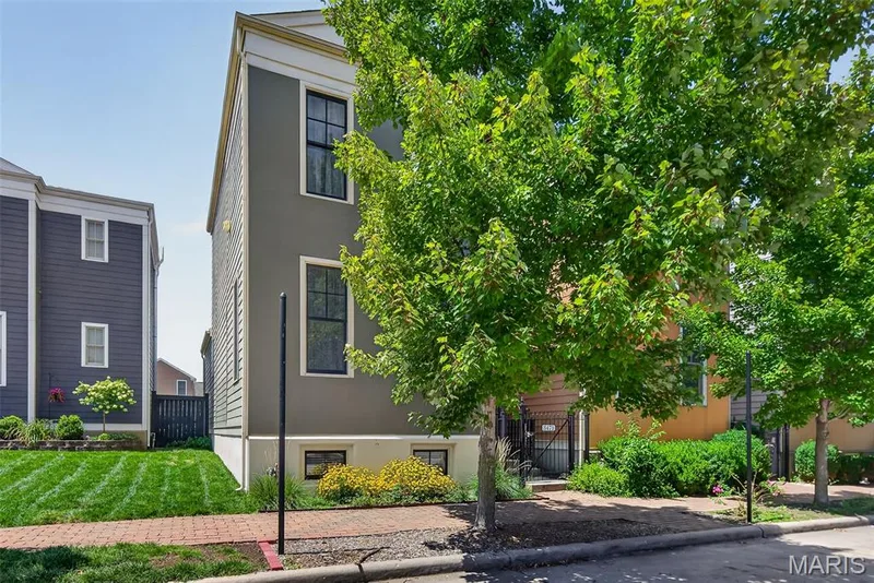 Modern townhome featuring a striking charcoal exterior with clean architectural lines, large multi-pane windows, and a brick-lined entry courtyard — 3471 Hiram Street, St Charles, MO 63301