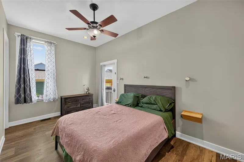 Spacious bedroom featuring wood-finish flooring, a ceiling fan with integrated lighting, and large window with natural light — 3471 Hiram Street, St Charles, MO 63301