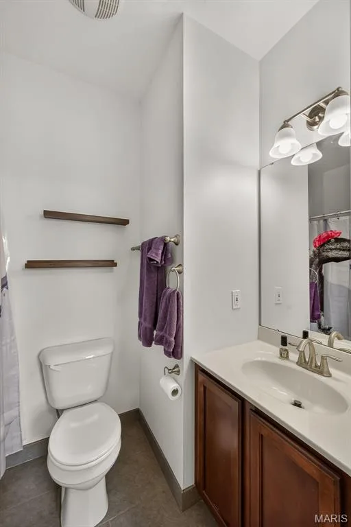 Elegant bathroom featuring a wood-finish vanity with dual-basin sink, brushed nickel faucet, and ample countertop space — 3471 Hiram Street, St Charles, MO 63301