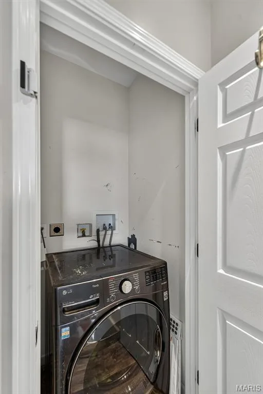 Dedicated laundry closet featuring a front-load washer/dryer combination unit, black stainless steel finish, white painted trim, and neutral wall surfaces with electrical outlet access — 3471 Hiram Street, St Charles, MO 63301