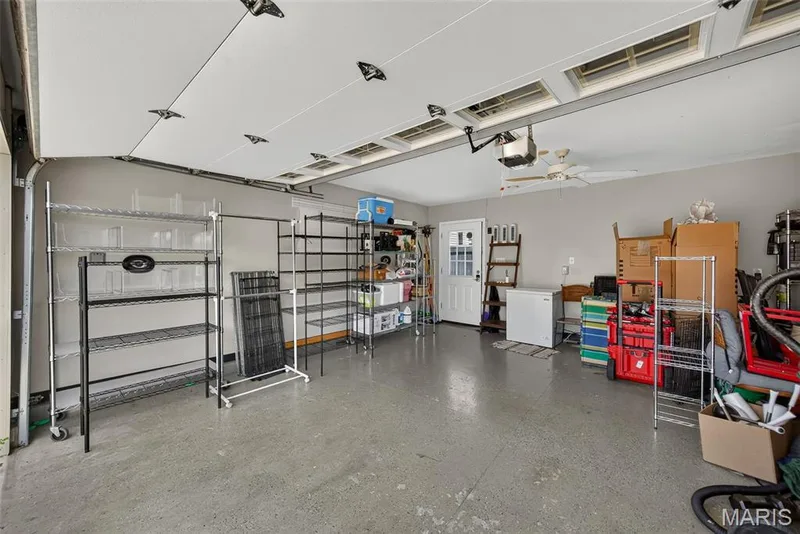 Spacious garage featuring polished concrete flooring, recessed ceiling lighting, overhead storage systems, and direct vehicle access — 3471 Hiram Street, St Charles, MO 63301