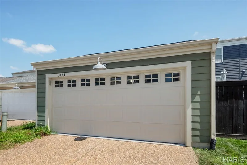 Detached garage with a paneled door, upper window inserts, and a gooseneck light fixture — 3471 Hiram Street, St Charles, MO 63301
