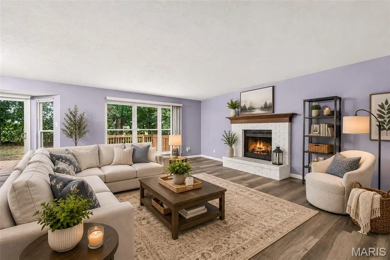Living room featuring wood-finish flooring, a white brick-surround fireplace with a wood mantle, and sliding glass doors opening to the exterior — 2947 Bromley Drive, O'Fallon, MO 63368