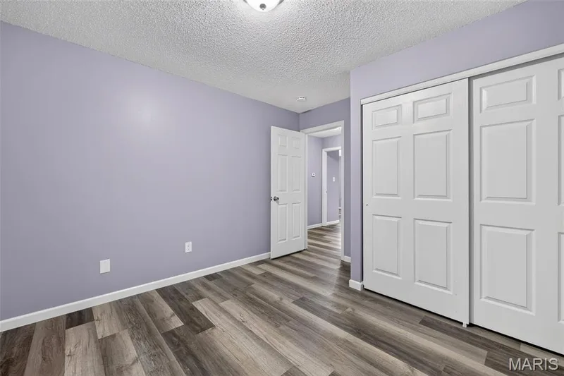 Bedroom featuring wood-finish flooring, light purple wall paint, and white baseboards — 2947 Bromley Drive, O'Fallon, MO 63368