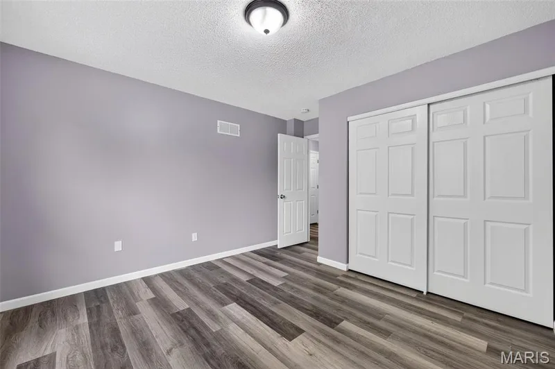 Room featuring wood-finish flooring, white baseboards, and a neutral wall color — 2947 Bromley Drive, O'Fallon, MO 63368