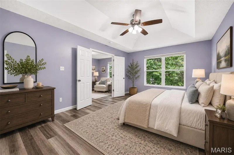 Spacious bedroom featuring wood-finish flooring, a tray ceiling, and a ceiling fan — 2947 Bromley Drive, O'Fallon, MO 63368