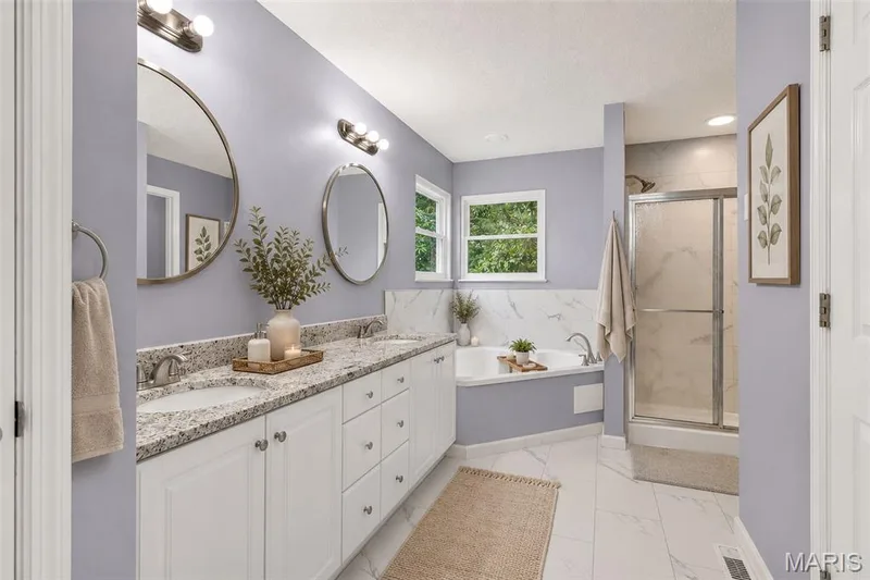 Spa-inspired primary bathroom featuring dual vanities with granite countertops, polished chrome fixtures, and ample storage — 2947 Bromley Drive, O'Fallon, MO 63368