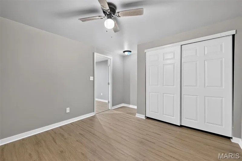 Spacious room with wood-finish flooring, light grey walls, and white baseboards — 2947 Bromley Drive, O'Fallon, MO 63368