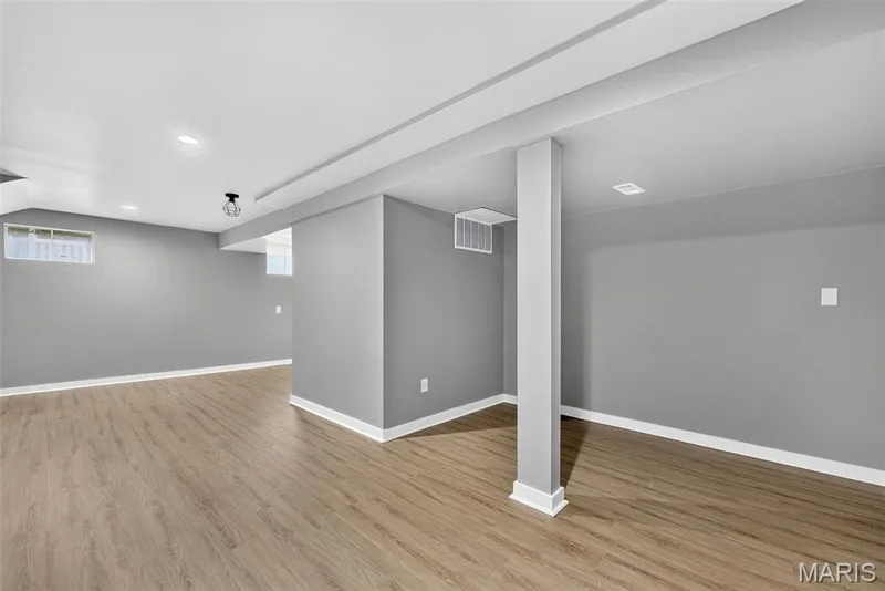 Spacious finished lower level with wood-finish flooring, recessed lighting, and a modern ceiling fixture — 2947 Bromley Drive, O'Fallon, MO 63368