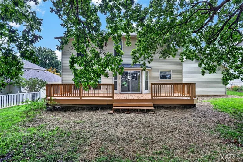 Spacious rear deck with wooden railing and steps, accessed by sliding glass doors from the home's siding exterior — 2947 Bromley Drive, O'Fallon, MO 63368