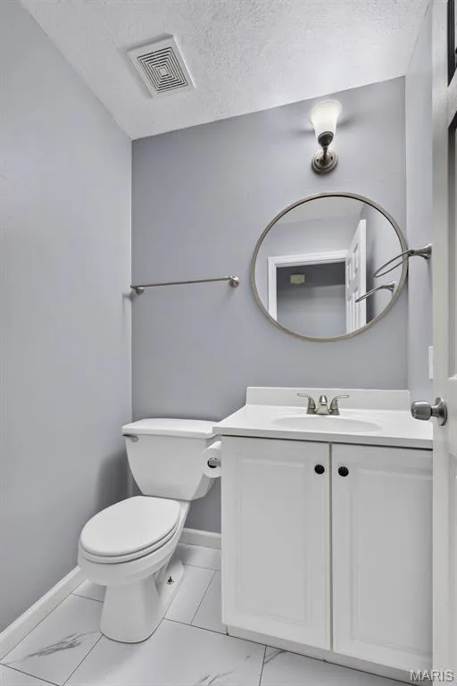 Full bathroom featuring a white vanity with paneled doors, a round mirror, and a wall-mounted light fixture — 2947 Bromley Drive, O'Fallon, MO 63368