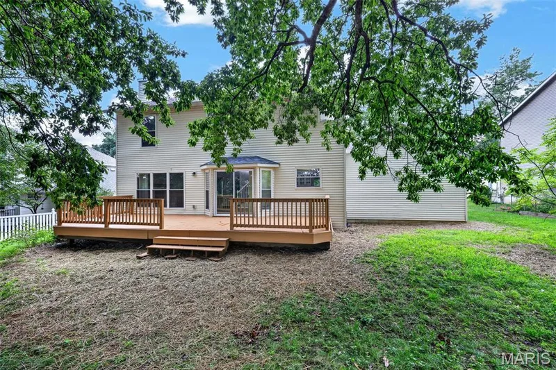 Spacious wood deck with multiple levels and integrated steps, offering direct access to the interior via a sliding glass door and a bay window — 2947 Bromley Drive, O'Fallon, MO 63368
