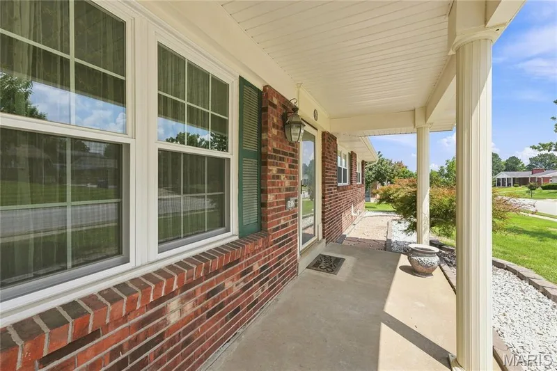 Brick exterior featuring a covered front porch with fluted columns and a concrete floor — 1613 Tamarack Drive, St Charles, MO 63301