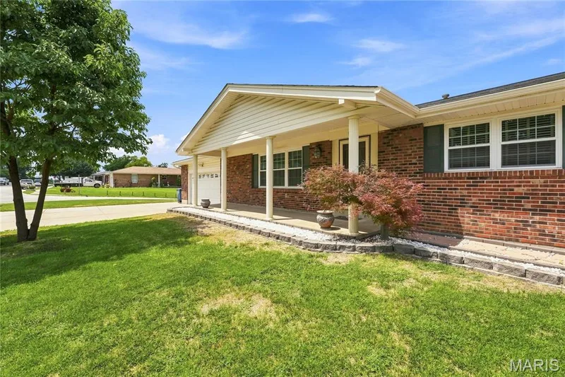 Brick exterior featuring a covered porch with white columns, attached garage. — 1613 Tamarack Drive, St Charles, MO 63301