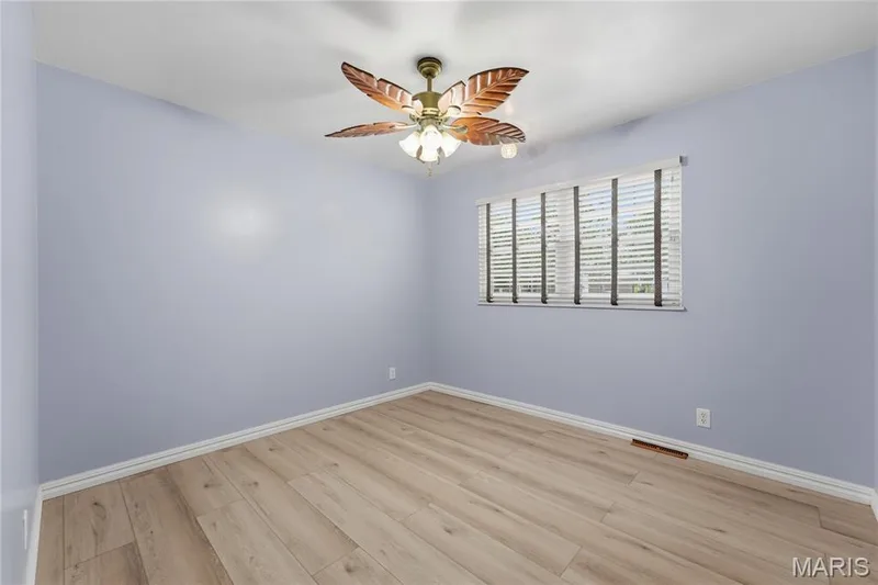 Room featuring wood-finish flooring, a ceiling fan with leaf-shaped blades, and a window with horizontal blinds — 1613 Tamarack Drive, St Charles, MO 63301