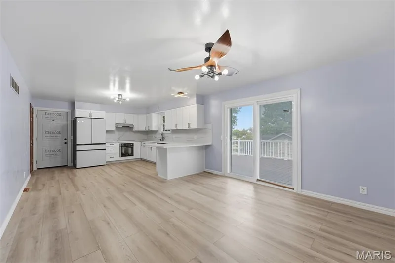 Expansive open-concept living area featuring light wood-finish flooring and a contemporary kitchen — 1613 Tamarack Drive, St Charles, MO 63301