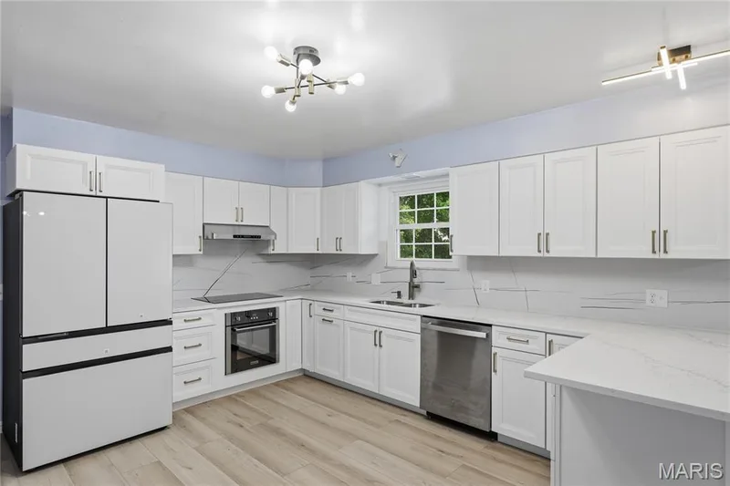 Kitchen featuring white shaker-style cabinetry, light wood-finish flooring, and white countertops — 1613 Tamarack Drive, St Charles, MO 63301
