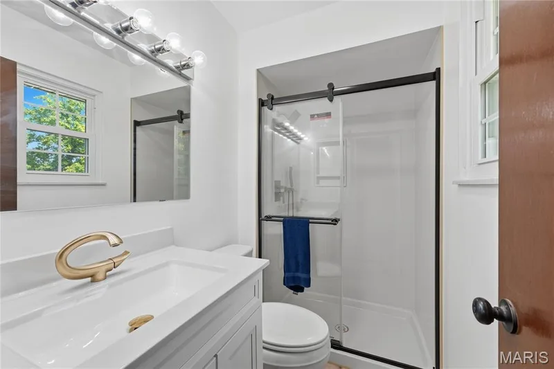 Primary Bathroom contemporary bathroom featuring a white vanity with an integrated sink, a brushed gold-tone faucet, and a large wall-mounted mirror — 1613 Tamarack Drive, St Charles, MO 63301