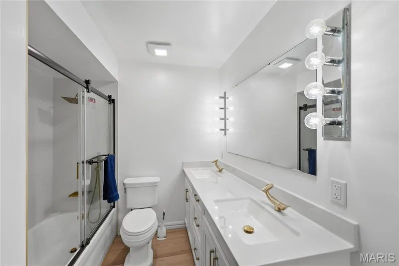 Modern bathroom featuring a dual-sink vanity with white quartz countertop, brushed gold hardware, and ample storage — 1613 Tamarack Drive, St Charles, MO 63301