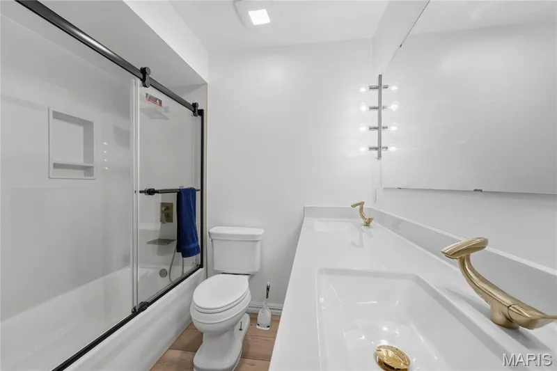 Bathroom featuring a dual vanity with white countertops, gold-tone fixtures, and integrated sinks — 1613 Tamarack Drive, St Charles, MO 63301