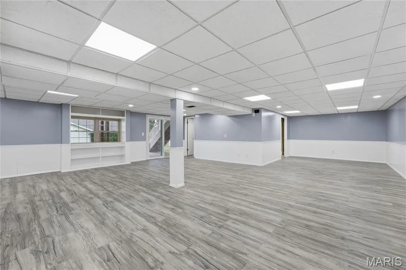 Spacious finished room featuring wide plank wood-finish flooring, drop ceiling with recessed lighting, and built-in shelving — 1613 Tamarack Drive, St Charles, MO 63301
