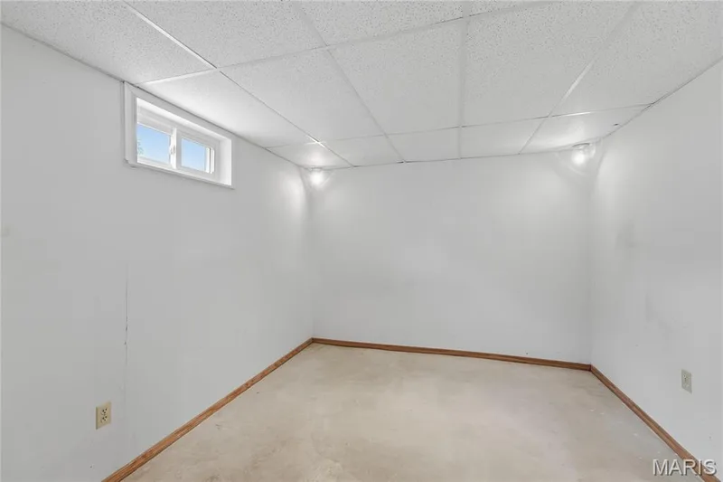 Carpeted room with white walls, wood-finish baseboards, and a drop ceiling — 1613 Tamarack Drive, St Charles, MO 63301