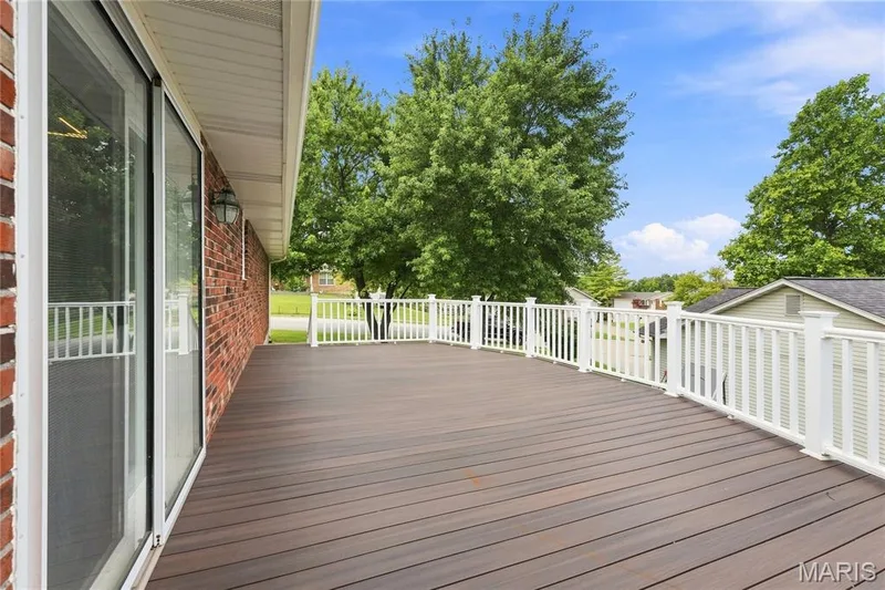 Expansive outdoor deck featuring composite decking, white vinyl railing, and direct access through a sliding glass door — 1613 Tamarack Drive, St Charles, MO 63301