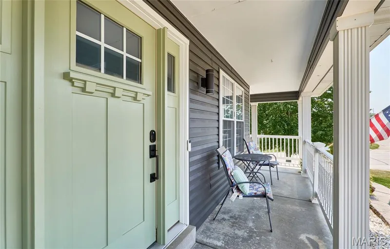 Inviting covered front porch featuring  white fluted columns, and a white railing — 3 Floral Court, O'Fallon, MO 63368