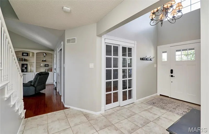 Foyer featuring ceramic tile flooring, a vaulted ceiling, and an ornate chandelier — 3 Floral Court, O'Fallon, MO 63368