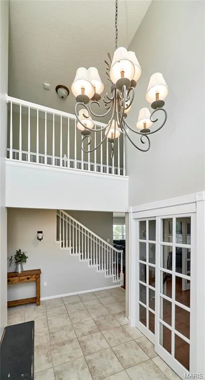 Two-story entryway with a decorative chandelier, tile flooring, and white spindle staircase — 3 Floral Court, O'Fallon, MO 63368