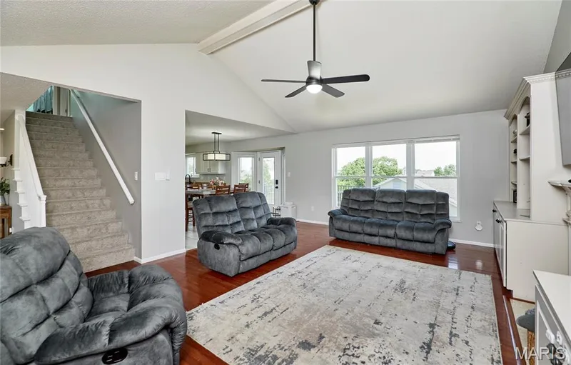 Spacious living area featuring high vaulted ceilings, wood-finish flooring, and a large picture window — 3 Floral Court, O'Fallon, MO 63368