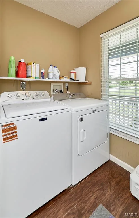 Dedicated utility space featuring wood-finish flooring, a wall-mounted shelf, and a window with horizontal blinds — 3 Floral Court, O'Fallon, MO 63368