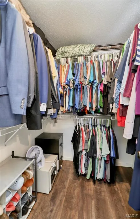 Walk-in closet featuring wood-finish flooring, white wire shelving, multiple hanging rods, and white painted walls — 3 Floral Court, O'Fallon, MO 63368