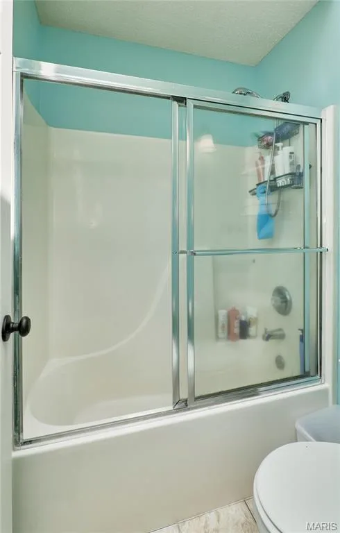 Tub and shower combination featuring sliding glass doors with chrome framing, a white tub enclosure, and a chrome shower fixture — 3 Floral Court, O'Fallon, MO 63368