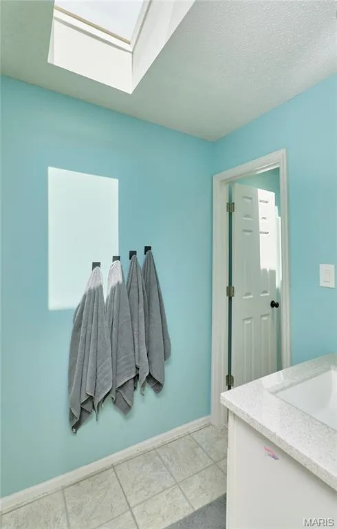 Skylight feature illuminating a bathroom with light blue walls and a white paneled door — 3 Floral Court, O'Fallon, MO 63368