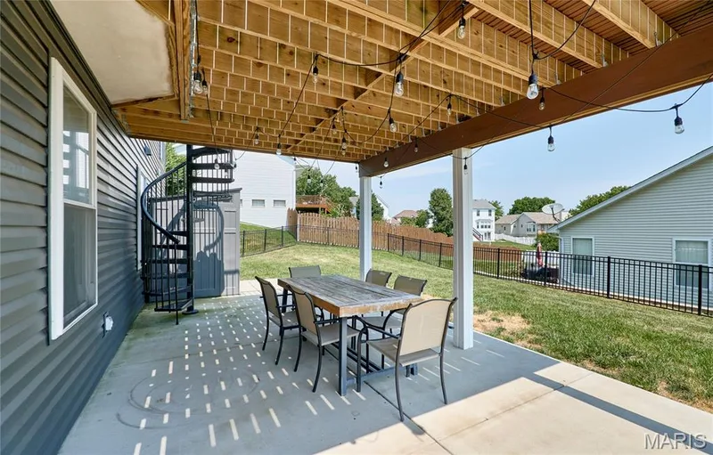 Expansive covered patio with composite decking, overhead lattice ceiling with integrated pendant lighting, and dining table seating for six — 3 Floral Court, O'Fallon, MO 63368