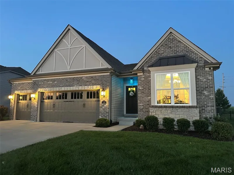 Brick and stone facade featuring a two-car garage with carriage-style doors and exterior sconce lighting — 110 Alta Mira Court, Dardenne Prairie, MO 63368