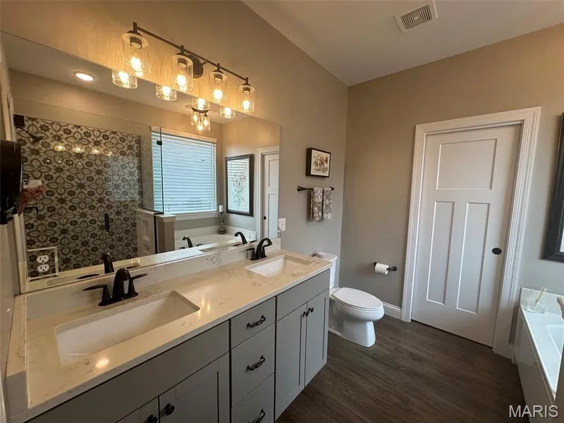 Dual vanity featuring undermount sinks, stone countertops, and dark bronze fixtures — 110 Alta Mira Court, Dardenne Prairie, MO 63368