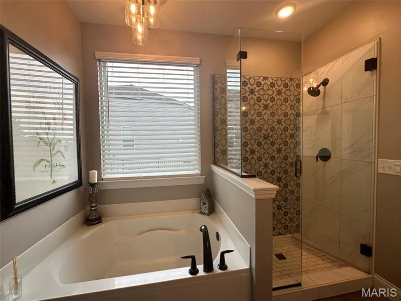 Soaking tub with black fixtures, framed by a window with white blinds — 110 Alta Mira Court, Dardenne Prairie, MO 63368