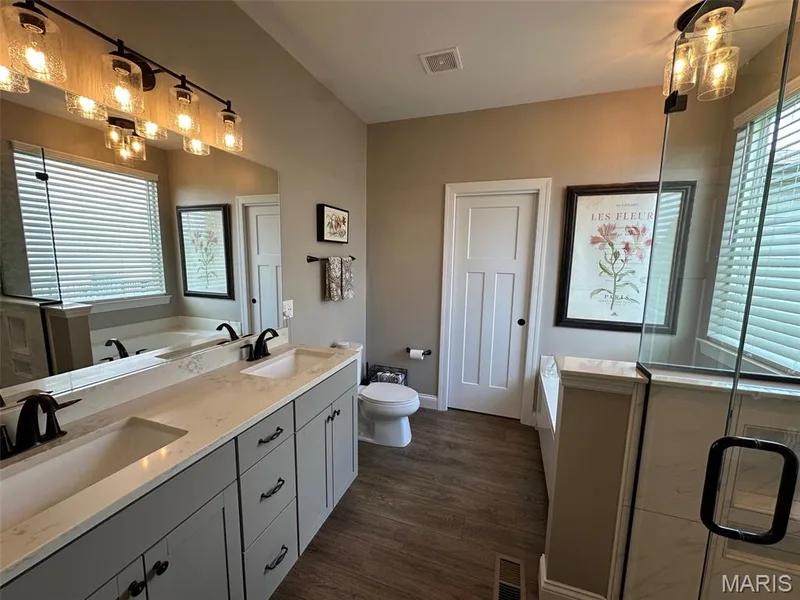 Dual vanity with matte black fixtures and light grey cabinetry set on wood-finish flooring — 110 Alta Mira Court, Dardenne Prairie, MO 63368