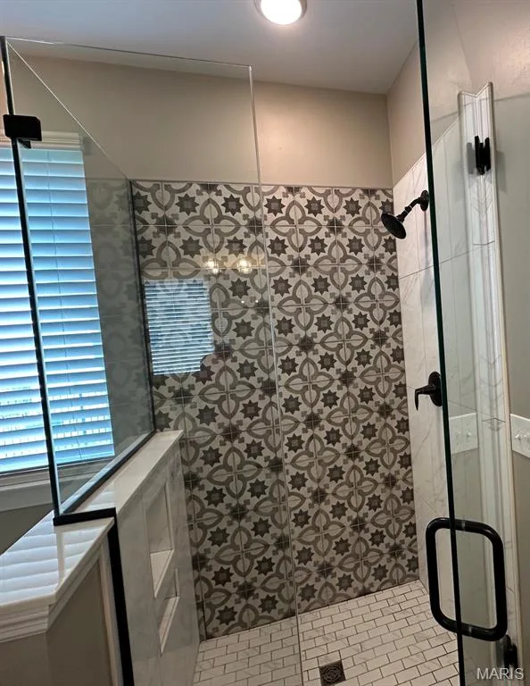 Glass-enclosed shower with patterned tile accent wall, matte black fixtures, and built-in shelving — 110 Alta Mira Court, Dardenne Prairie, MO 63368