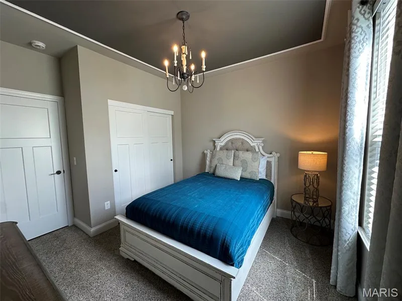 Bedroom featuring a contrasting dark ceiling with white crown molding, a multi-paneled door, and a built-in sliding door closet — 110 Alta Mira Court, Dardenne Prairie, MO 63368